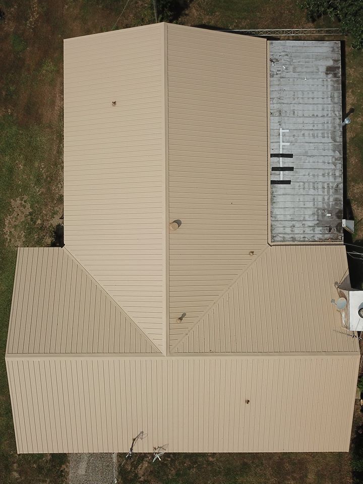 Overhead view of a tan metal roof building with a flat gray section attached.