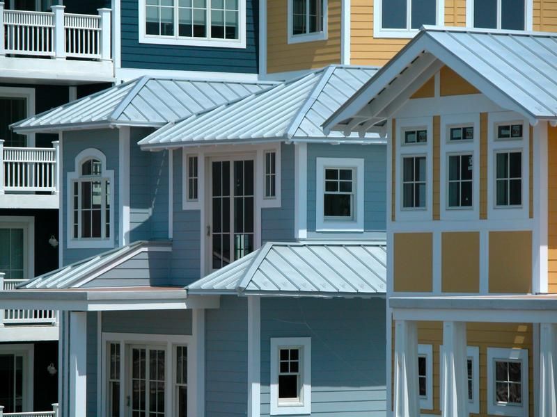Colorful houses with blue, yellow, and white accents and metal roofs.