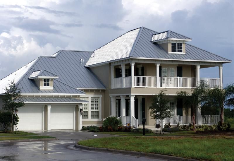 Two-story house with a gray metal roof and a second-floor balcony.