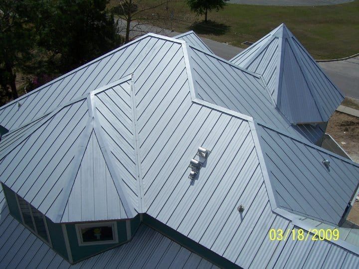 Silver metal roof with complex angles and ridges on a building.
