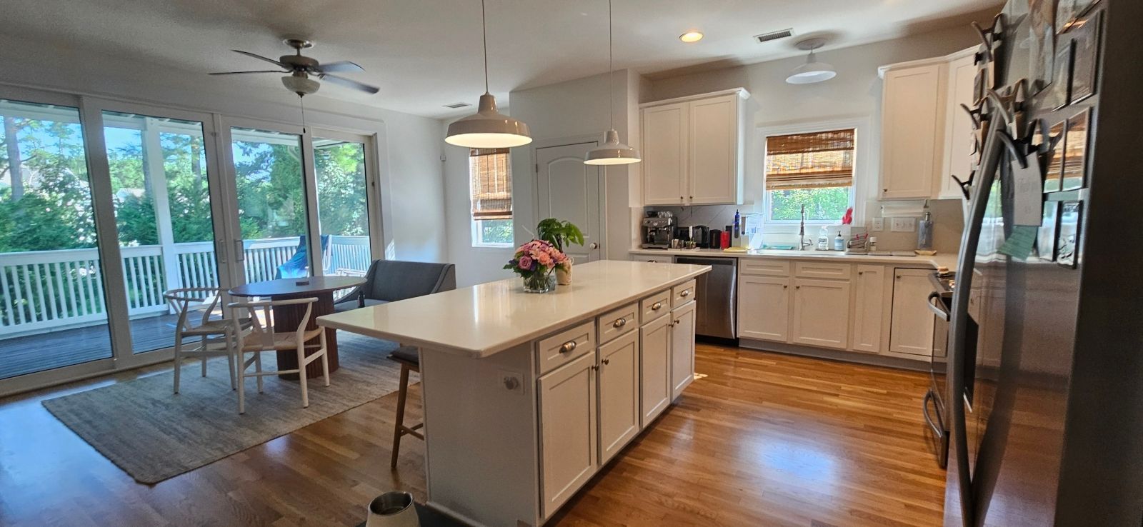 Kitchen with white cabinets, island, and large windows overlooking a deck.