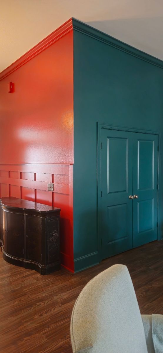 Interior with red and teal painted walls, wooden cabinet, and sofa.