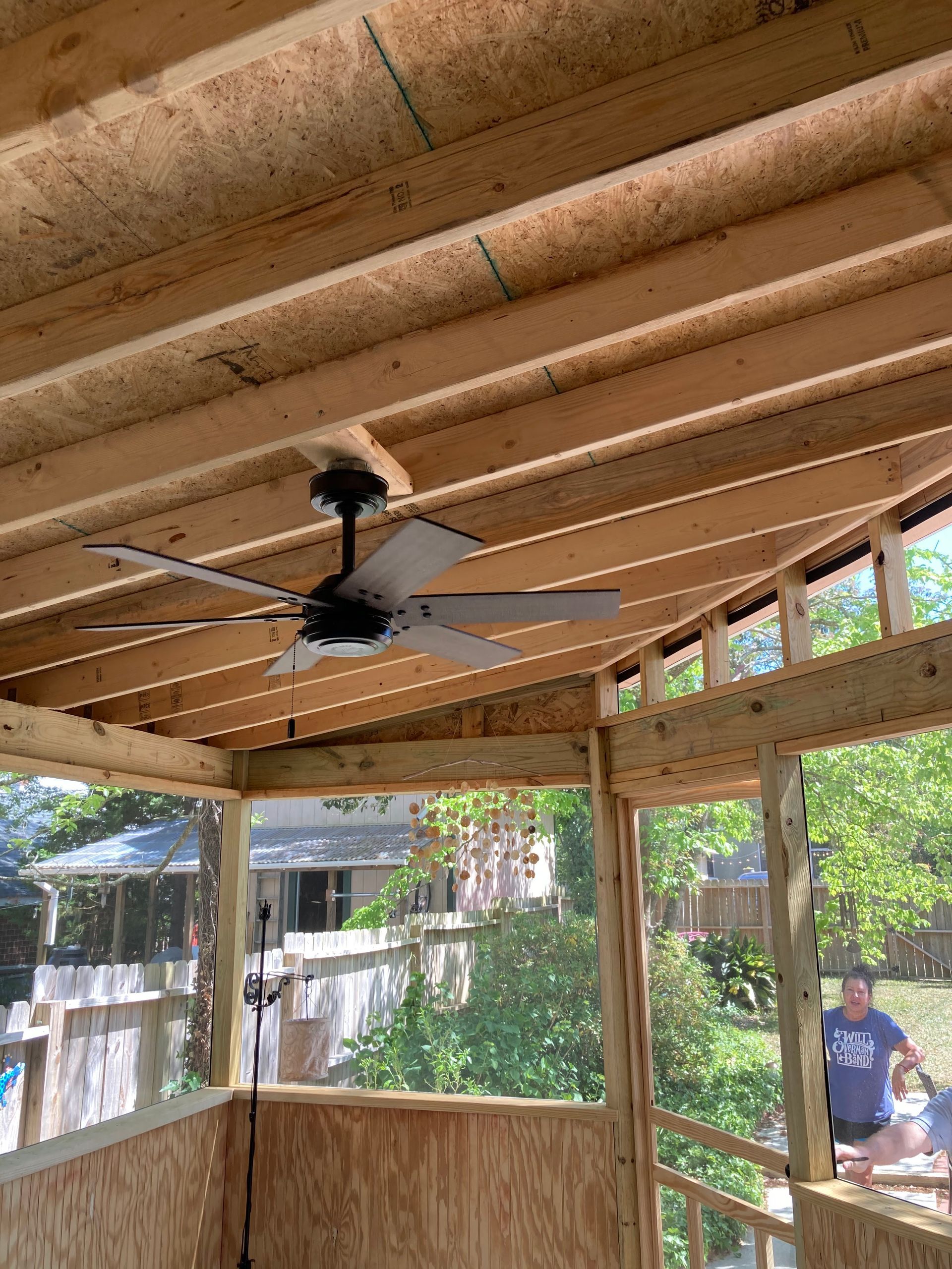 A ceiling fan is hanging from the ceiling of a wooden structure.
