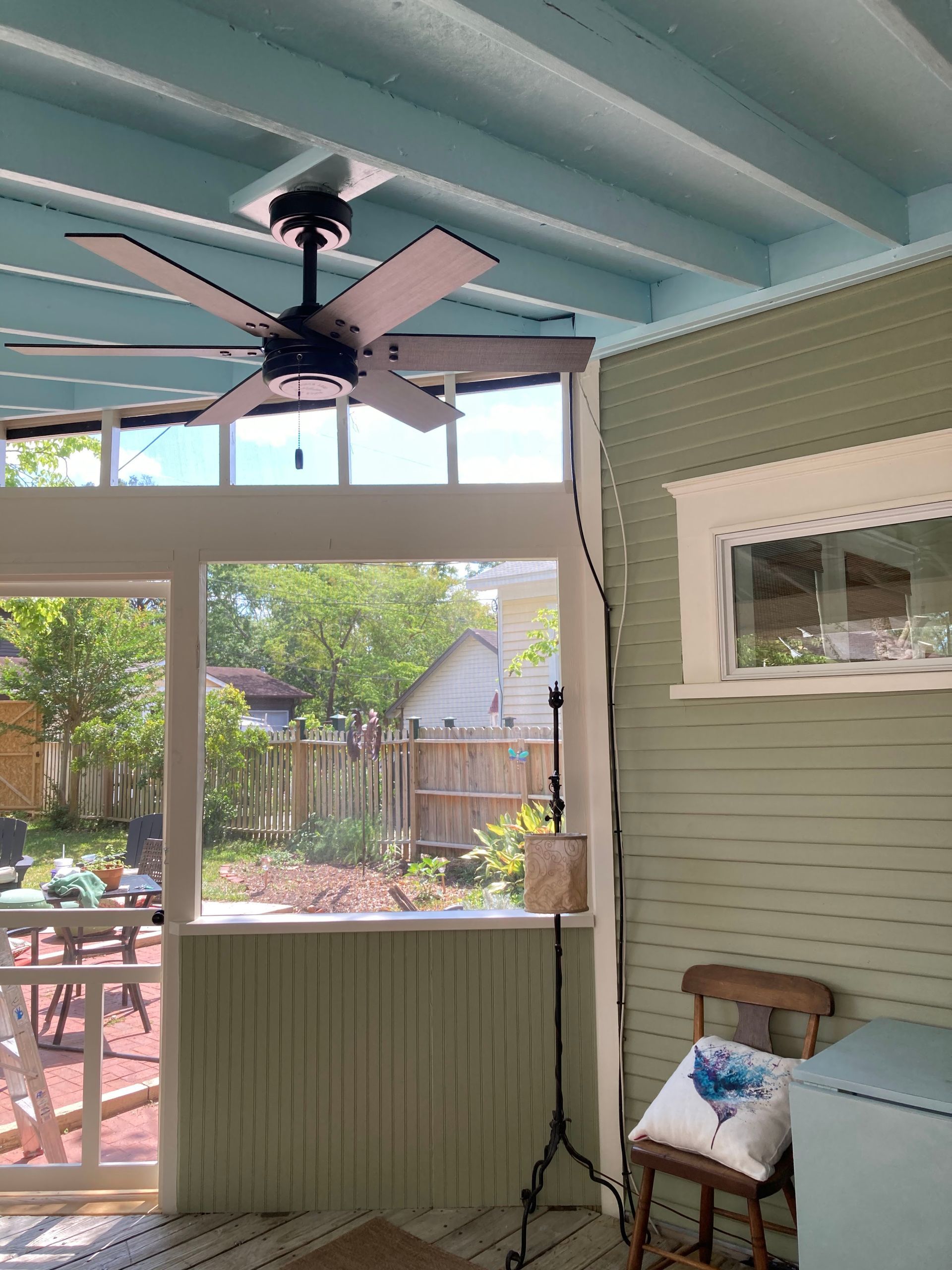 A screened in porch with a ceiling fan and a window