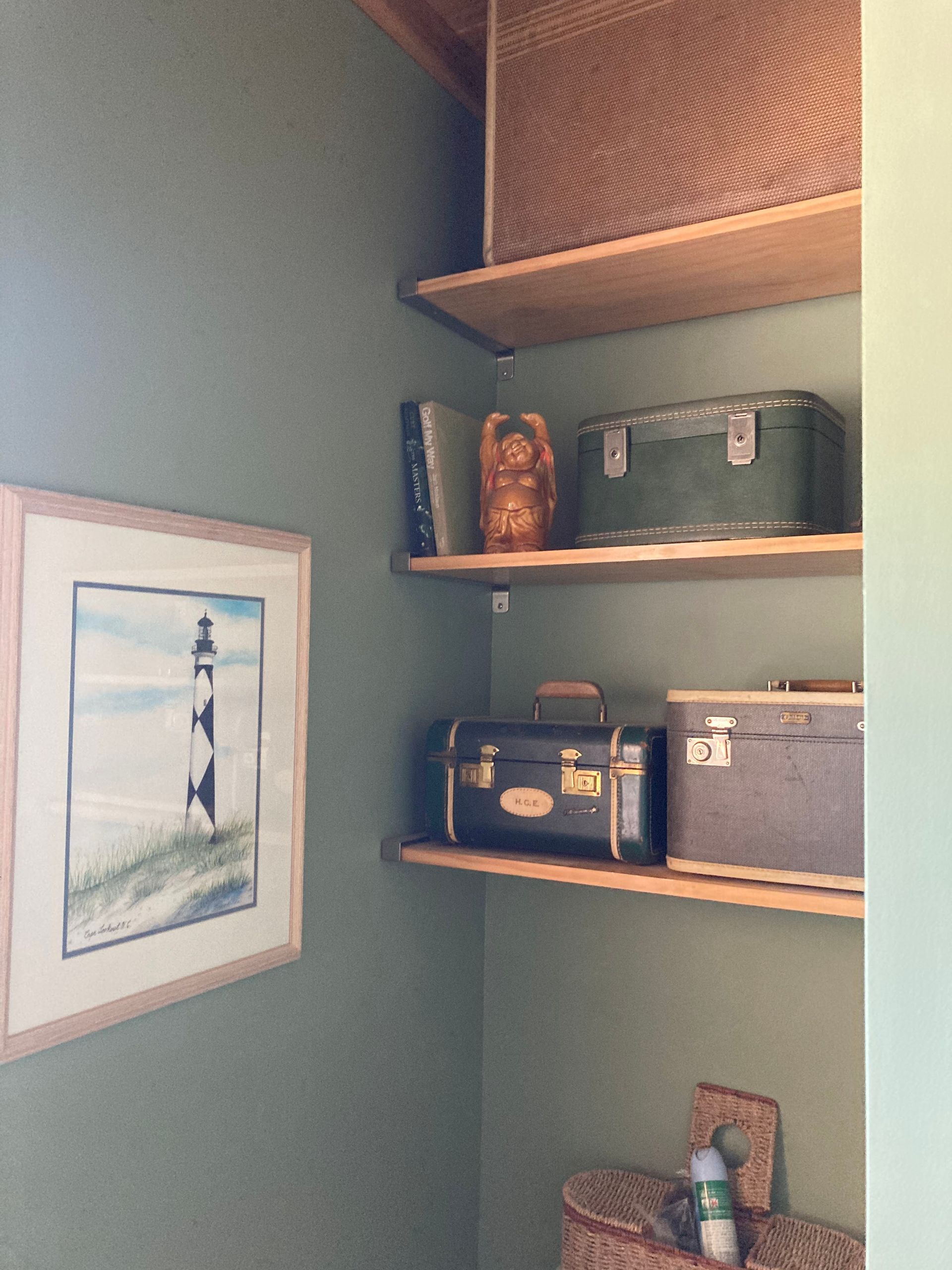 A corner of a room with shelves and a picture of a lighthouse on the wall
