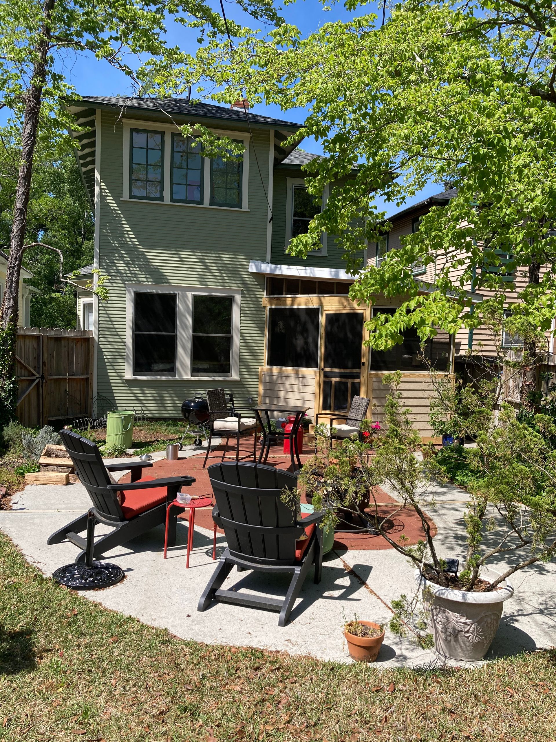 A patio with chairs and a table in front of a house.