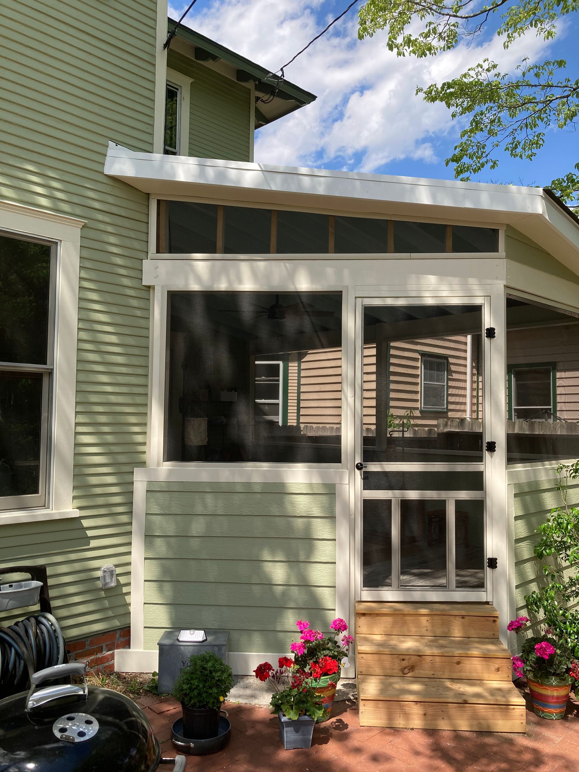 A screened in porch on the side of a house