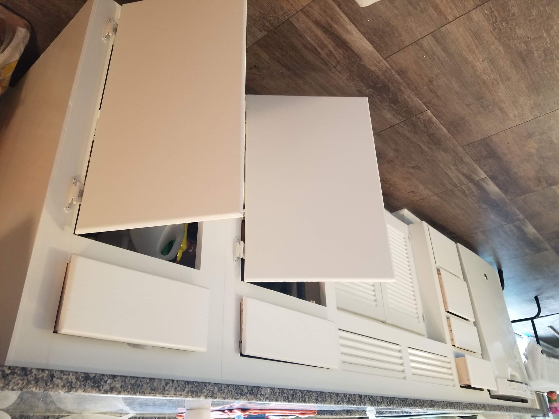 A kitchen with white cabinets and a wooden floor.