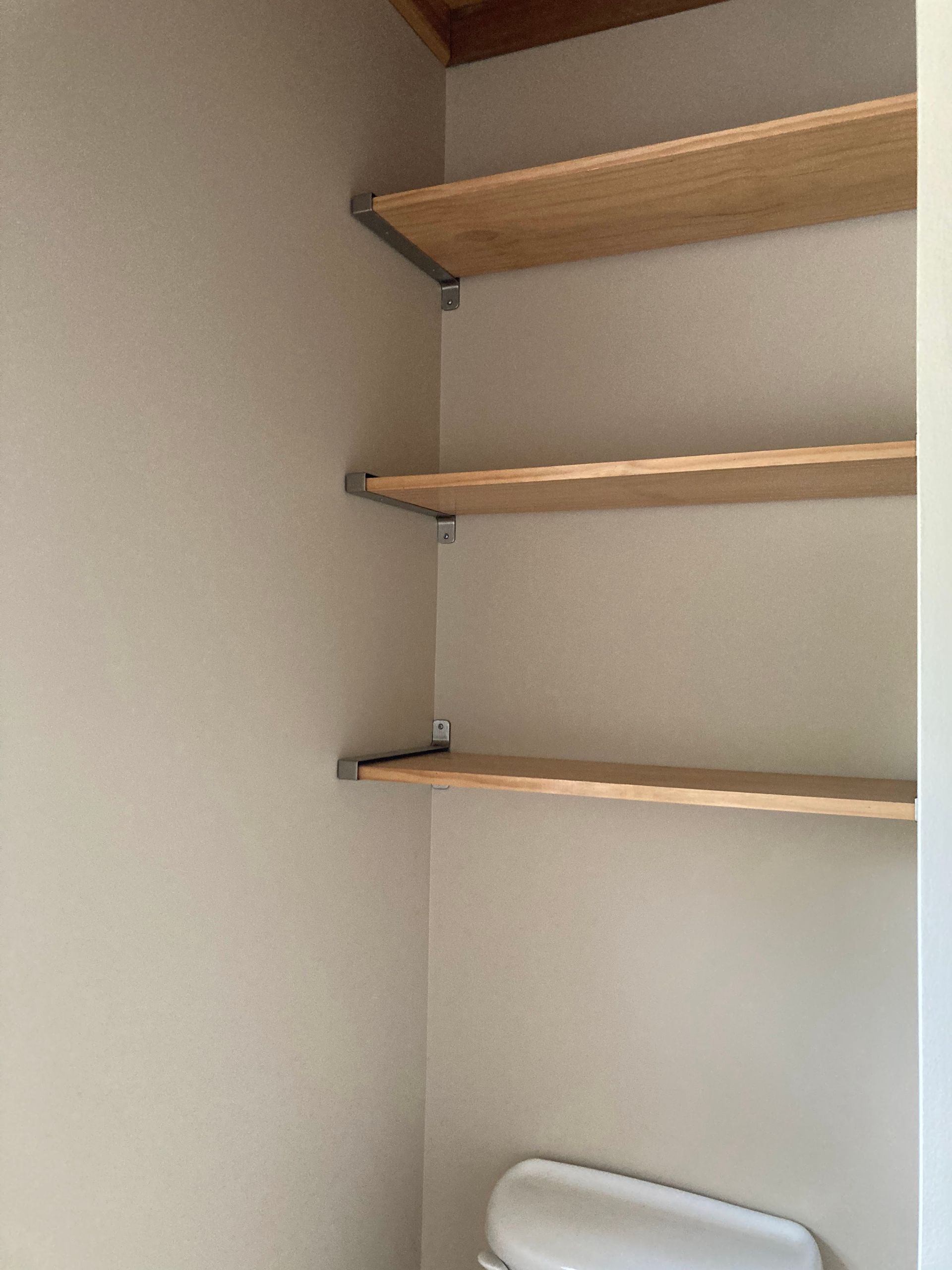 A bathroom with a toilet and shelves above it