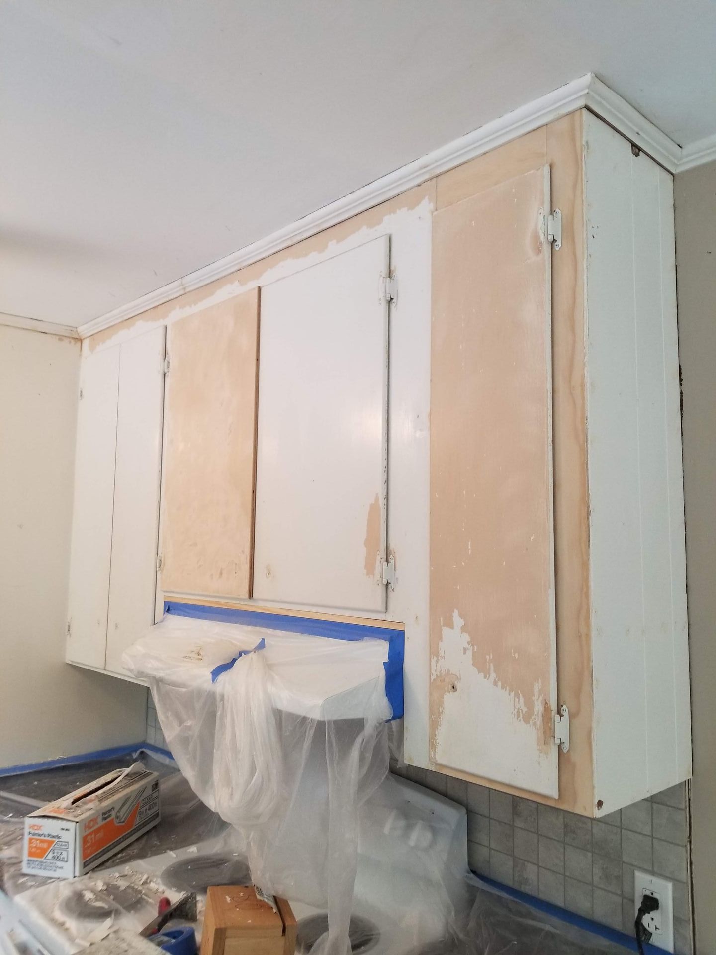 A kitchen cabinet is being painted with a blue tape.