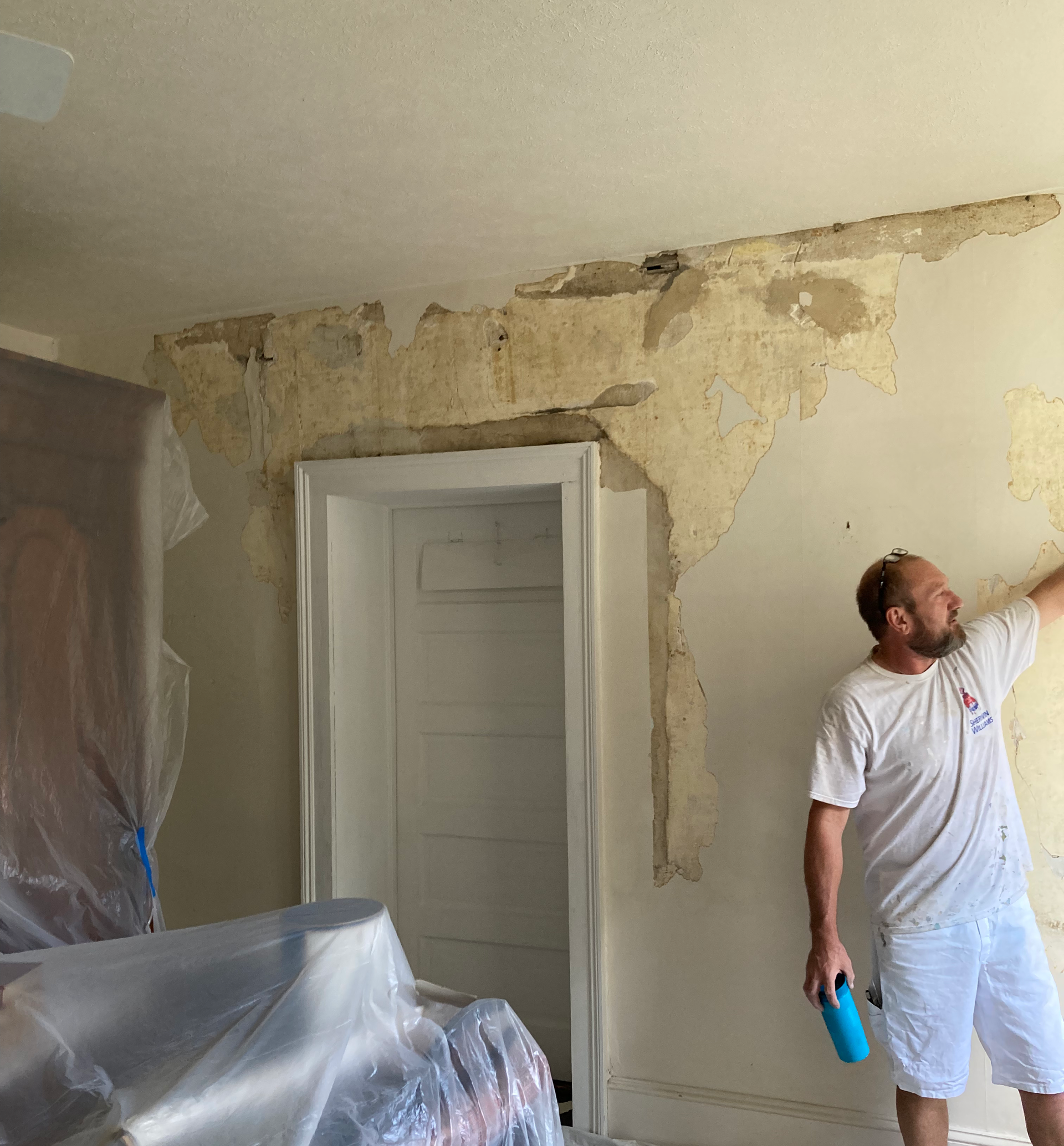 A man is painting a wall with a spray bottle