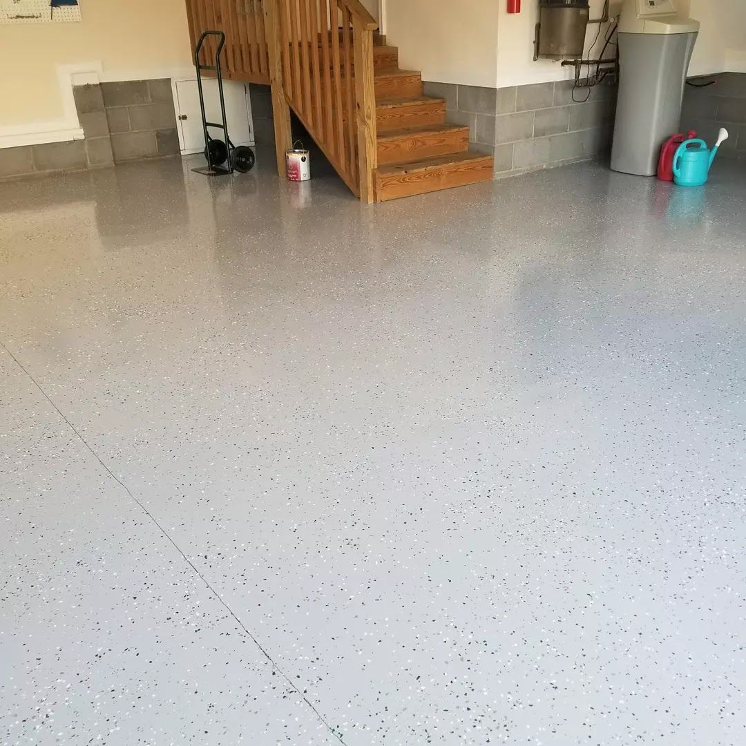 A garage with a staircase and a watering can on the floor.