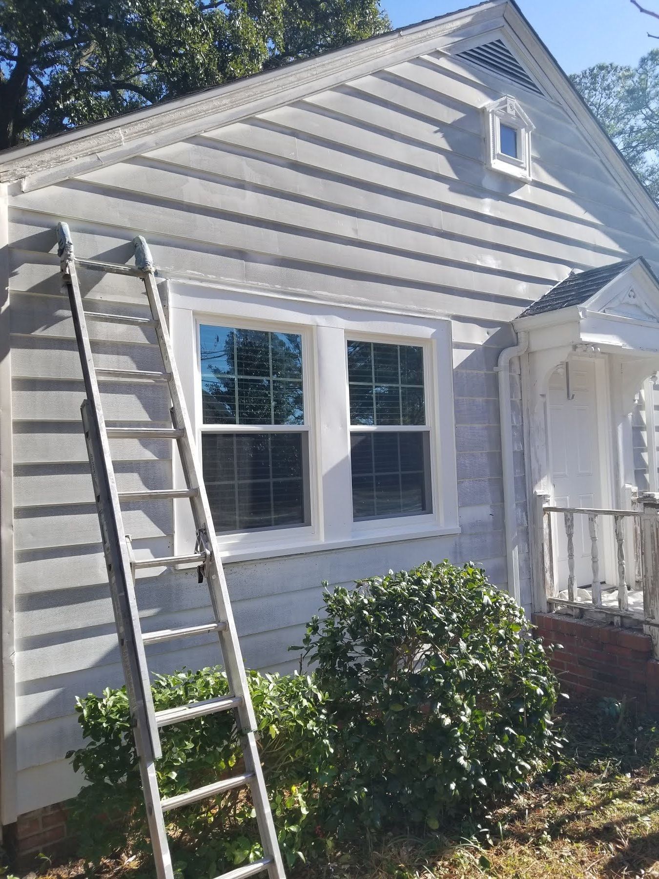 A white house with a ladder on the side of it.