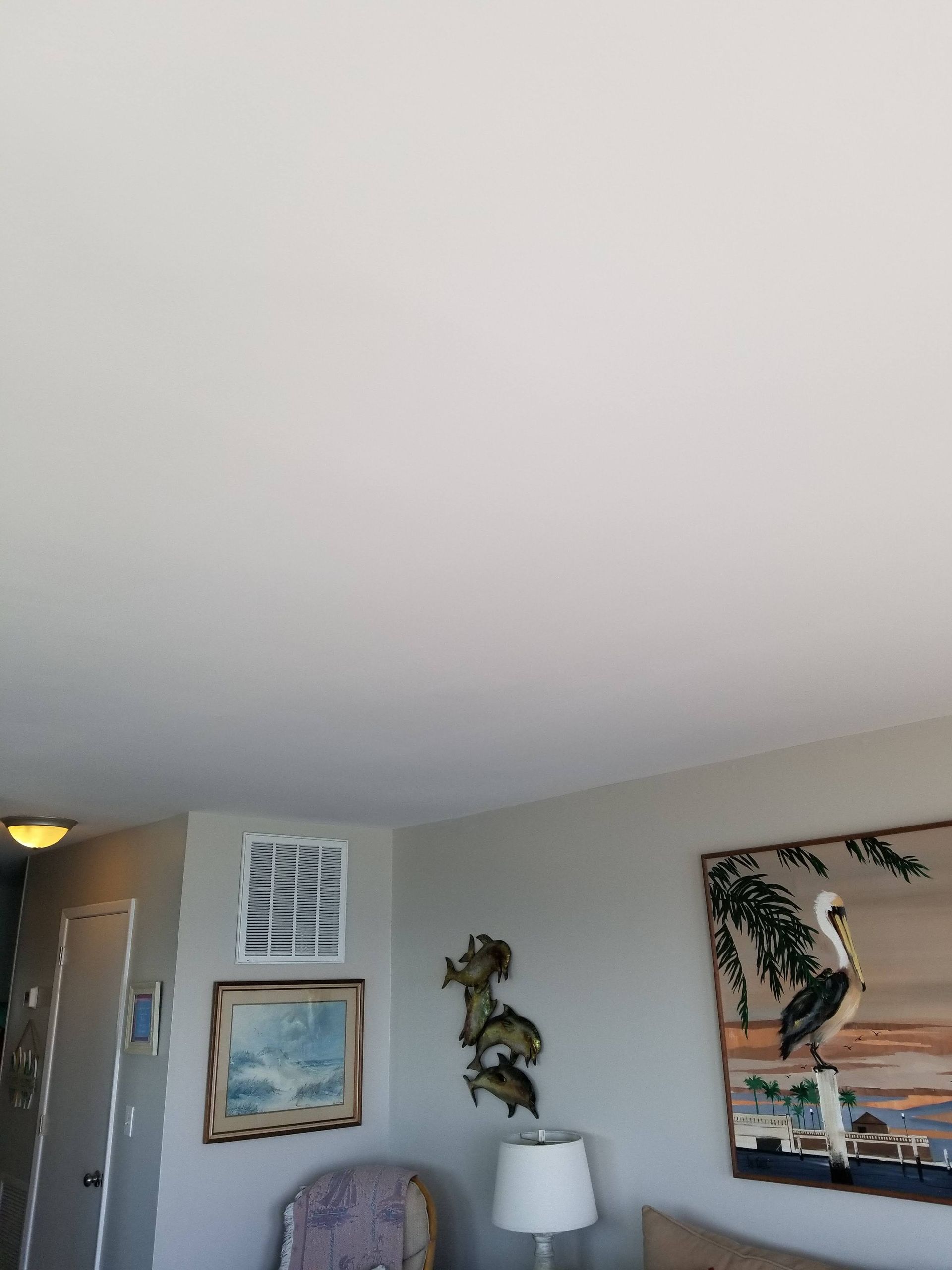 A living room with a white ceiling and paintings on the walls