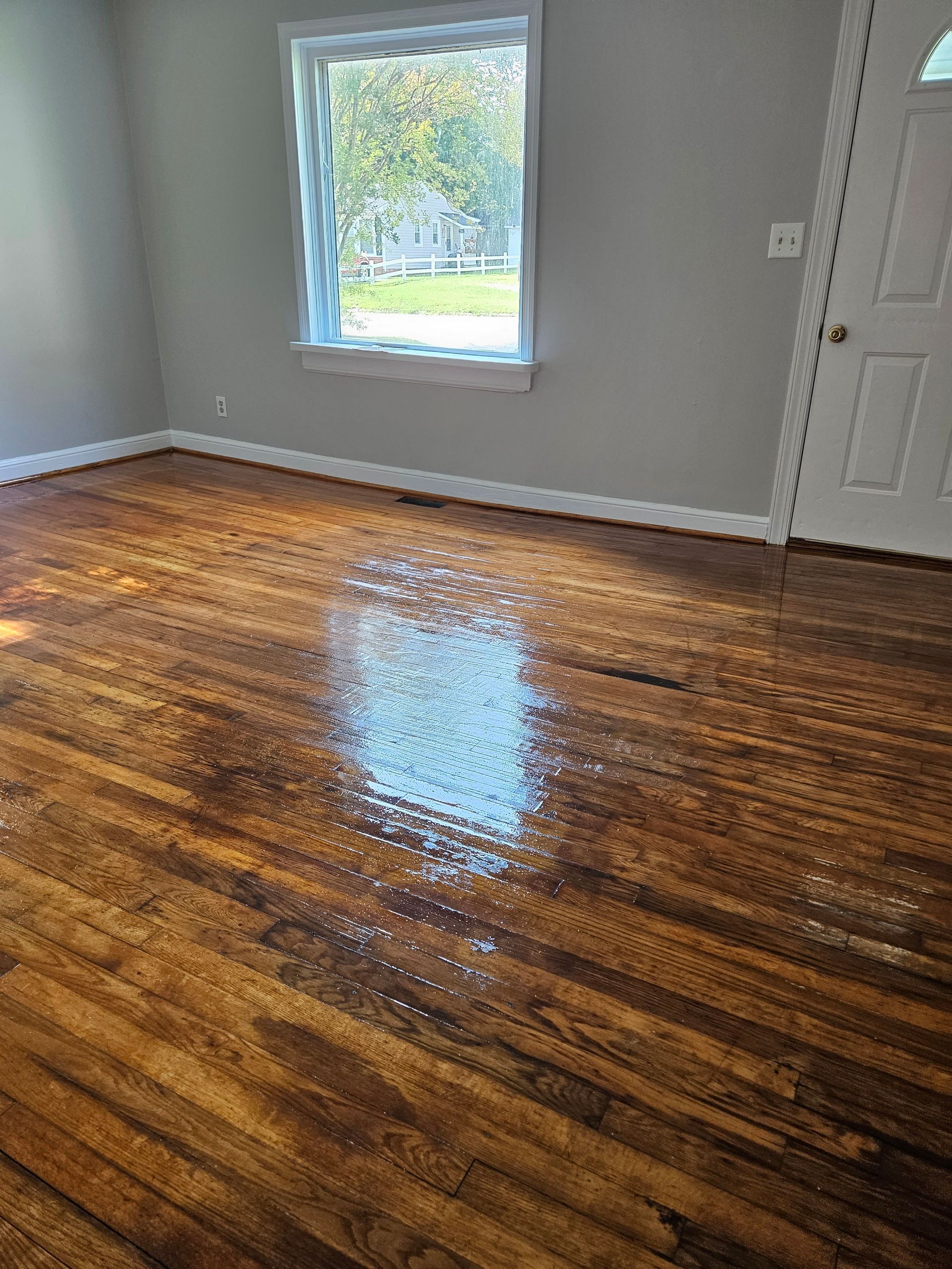 A living room with a wooden floor and a window.