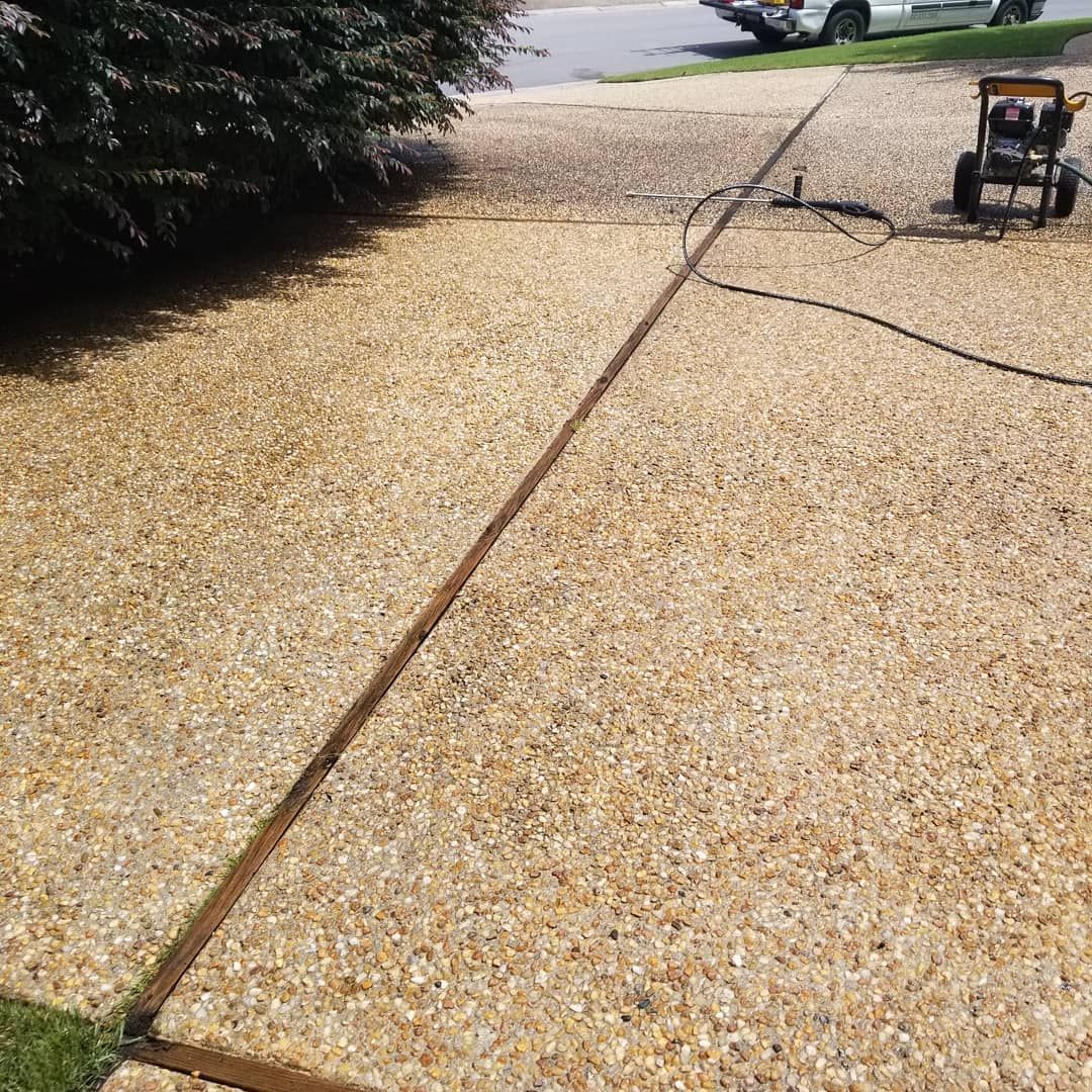 A concrete driveway is being cleaned with a pressure washer.