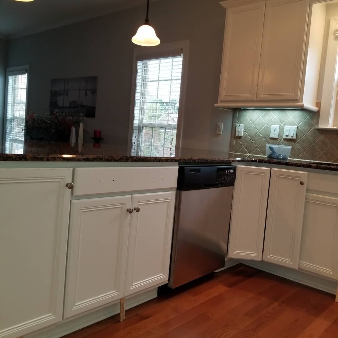 A kitchen with white cabinets and a stainless steel dishwasher