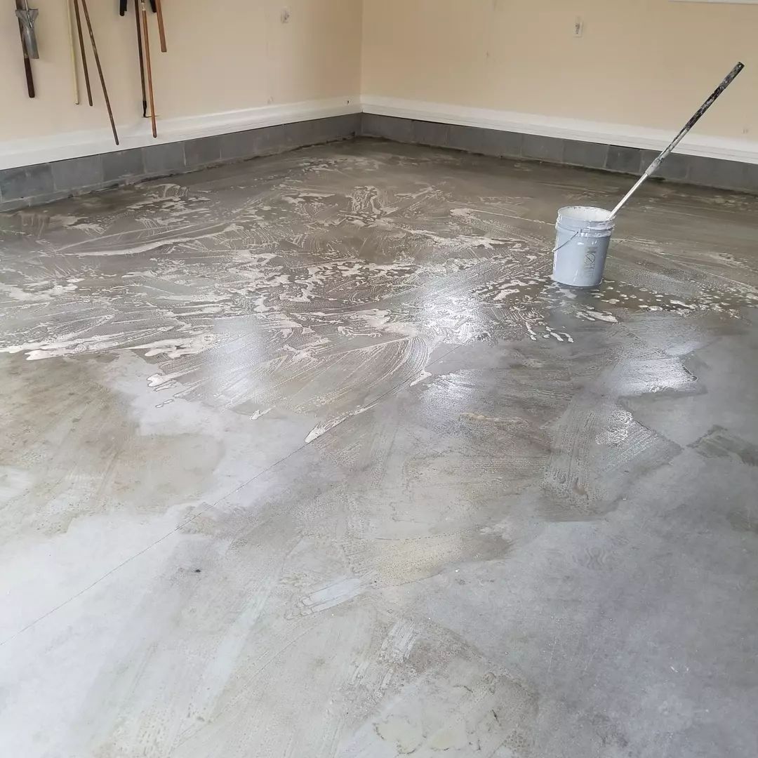 A concrete driveway is being cleaned with a pressure washer.