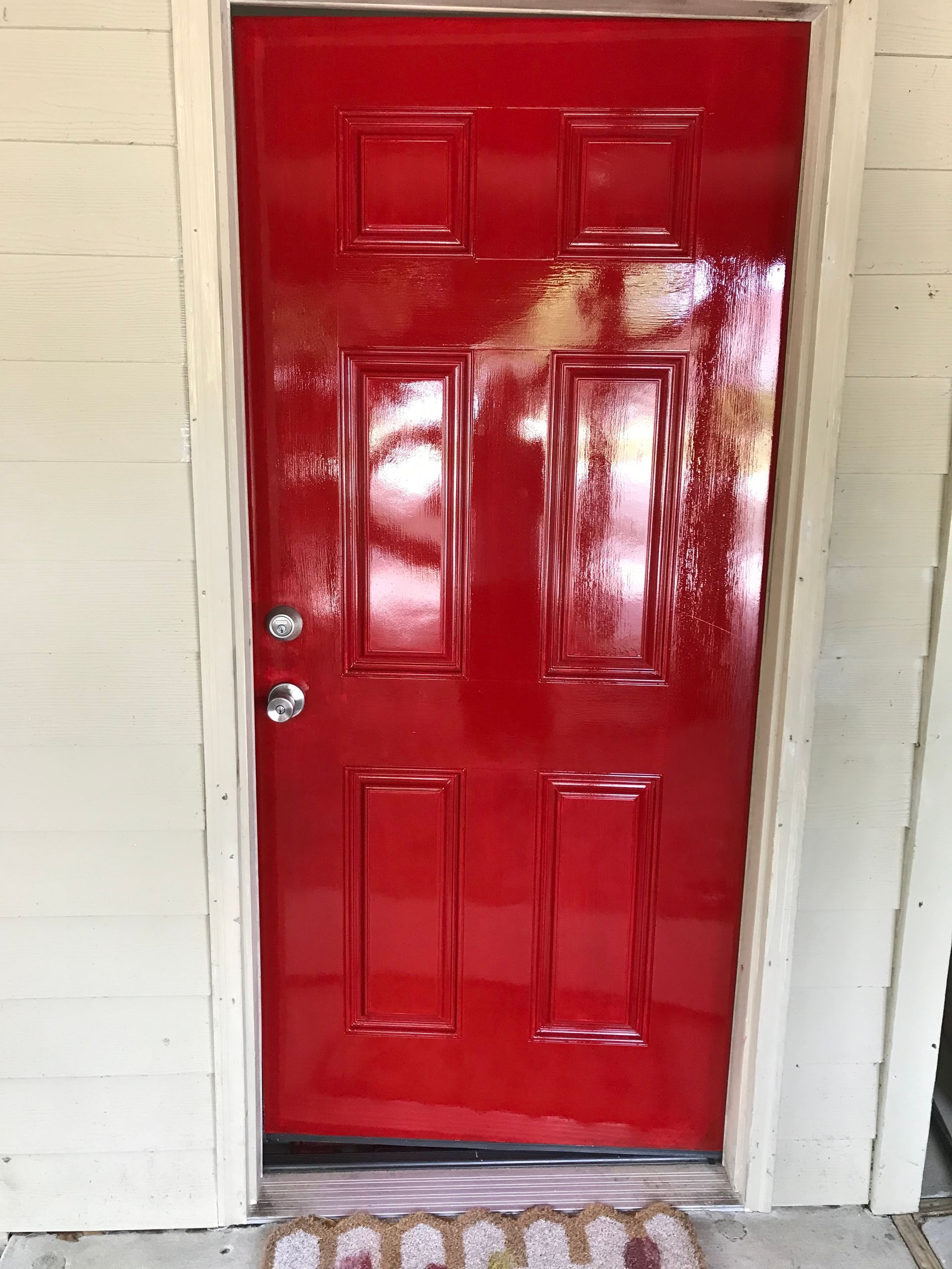 A red door is painted on the side of a white house.