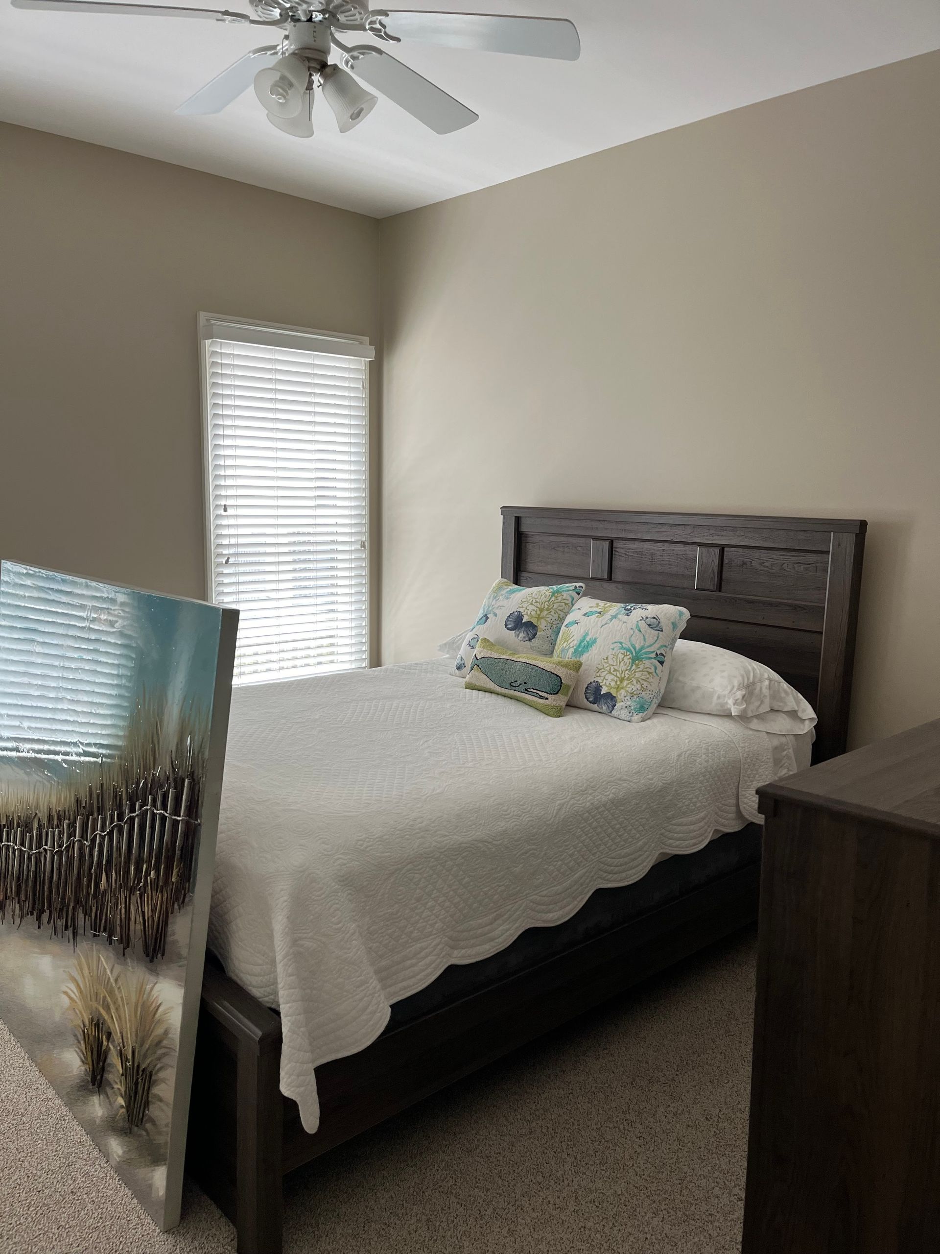 A bedroom with a bed , dresser , and ceiling fan.