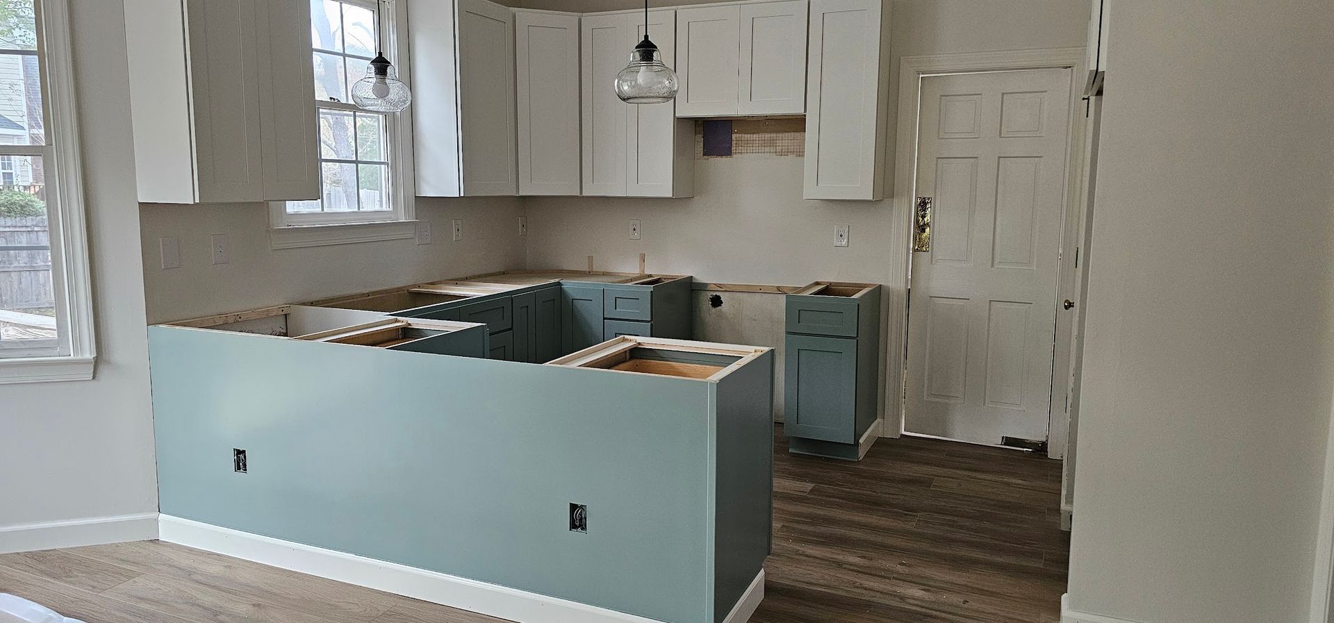 A kitchen with white cabinets and blue counter tops is being remodeled.