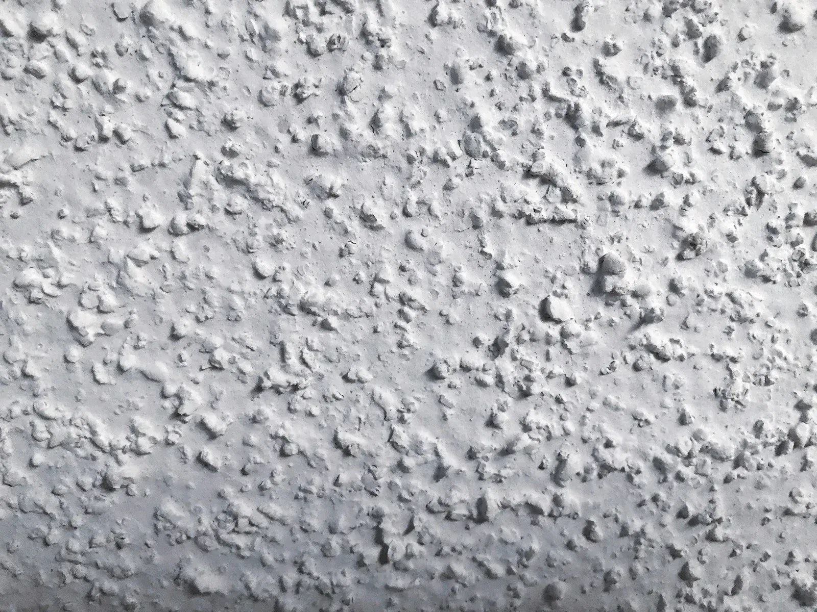 A man is painting the ceiling with a roller.