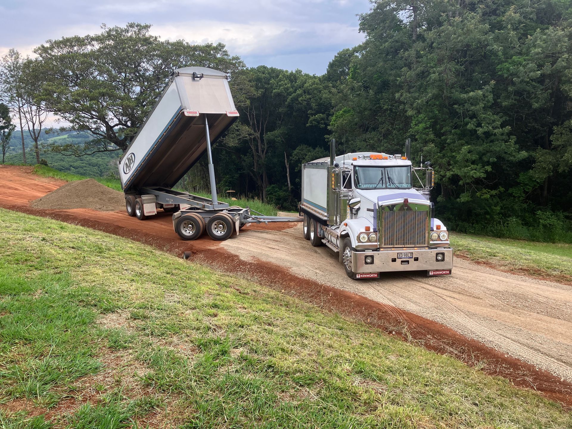 A Dump Truck is Driving Down a Dirt Road  — Andrew Johnston Haulage In Ewingsdale, NSW