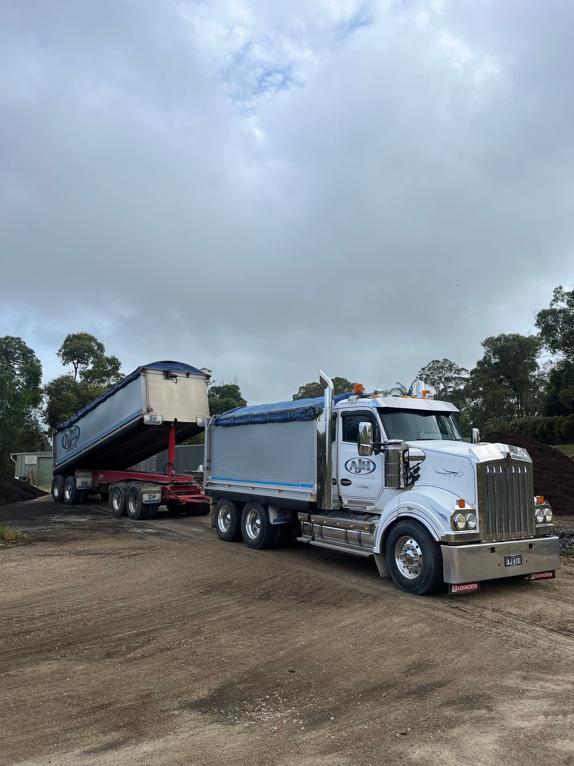 A Dump Truck With a Trailer Attached to It is Parked in a Dirt Lot  — Andrew Johnston Haulage In Ewingsdale, NSW