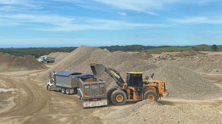 A Bulldozer is Loading a Dump Truck With Gravel — Andrew Johnston Haulage In Ewingsdale, NSW