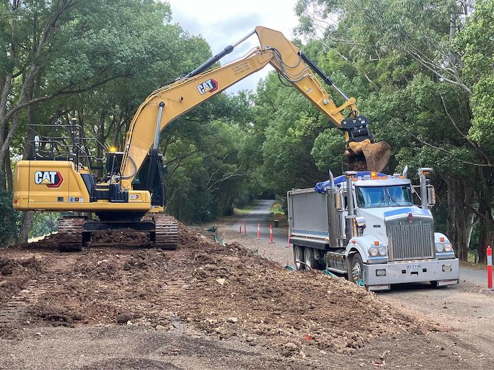 An Excavator Is Loading Dirt Into A Dump Truck — Andrew Johnston Haulage In Kyogle, NSW
