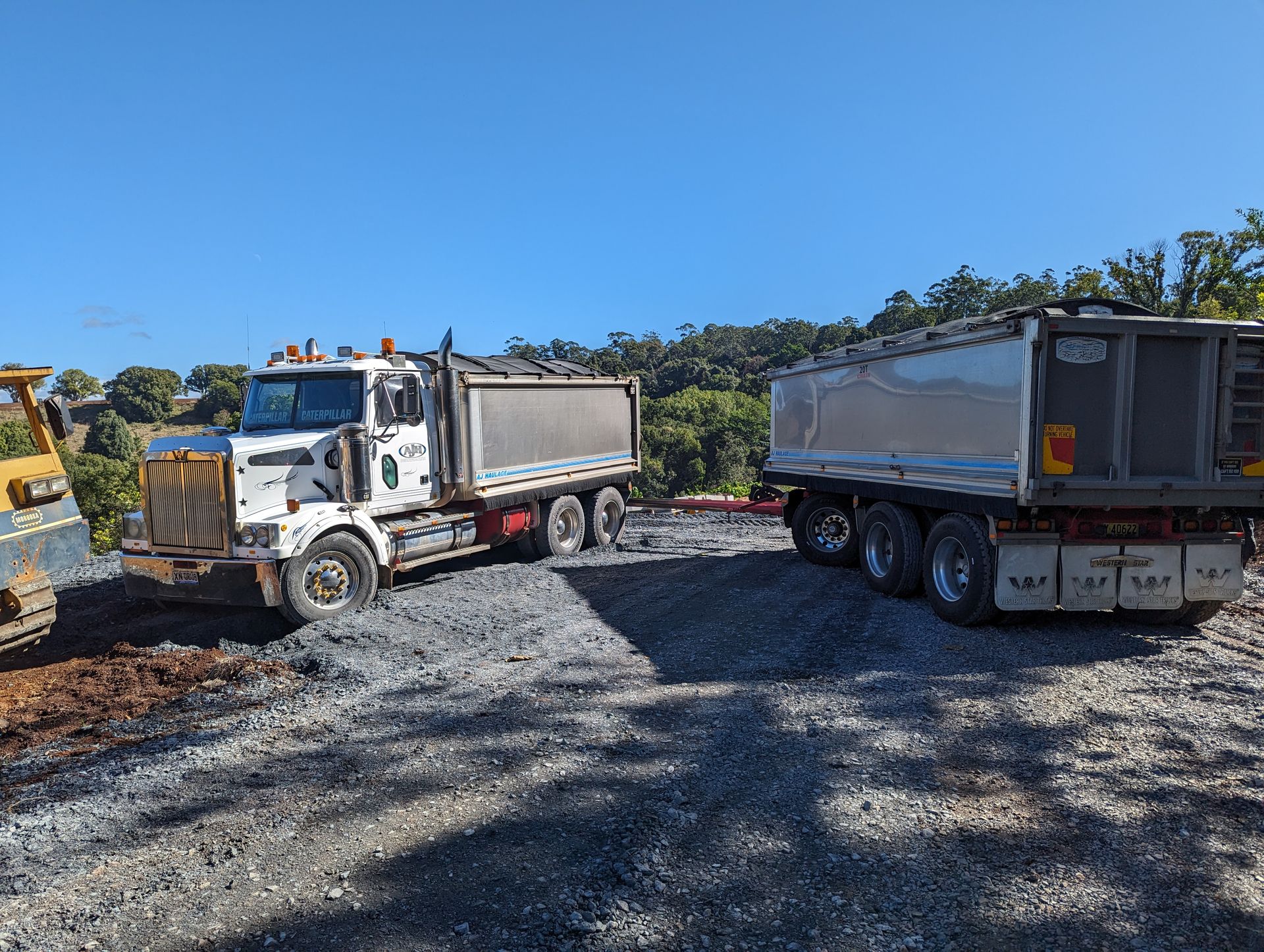 A Dump Truck is Parked Next to a Bulldozer on a Gravel Road — Andrew Johnston Haulage In Ewingsdale, NSW