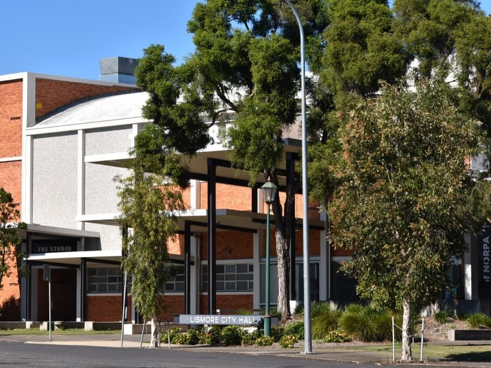 Brick and White Building Partially Obscured by Trees, With a Street Sign — Andrew Johnston Haulage In Lismore, NSW