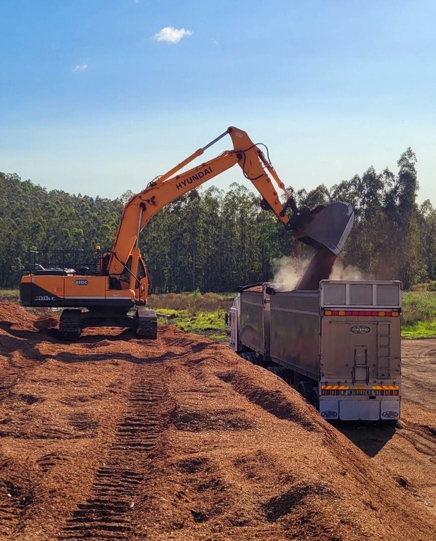 An Excavator is Loading Dirt Into a Dump Truck — Andrew Johnston Haulage In Ewingsdale, NSW