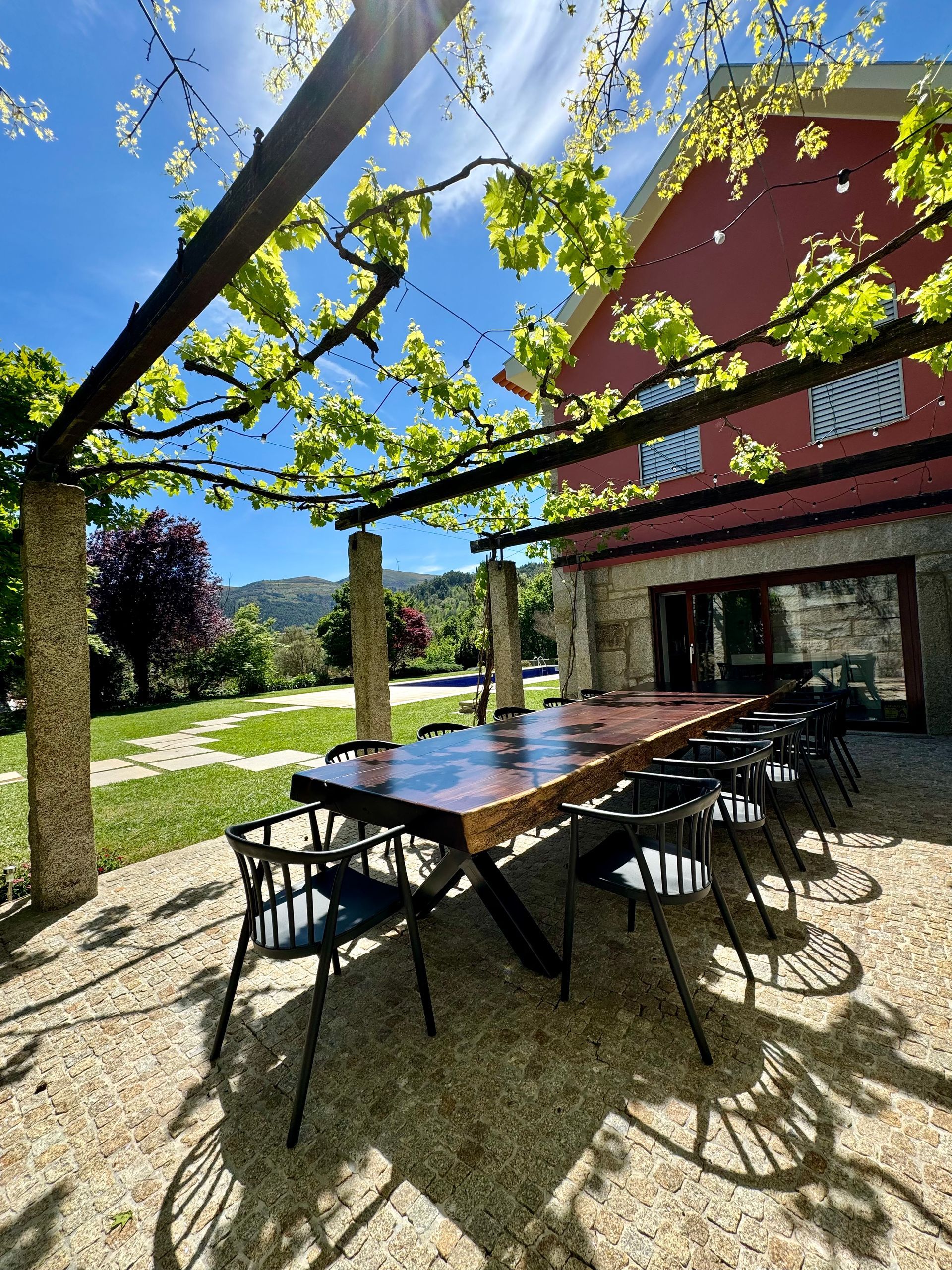 Kitchen terrace with a big wood table and a view of the pool and mountain