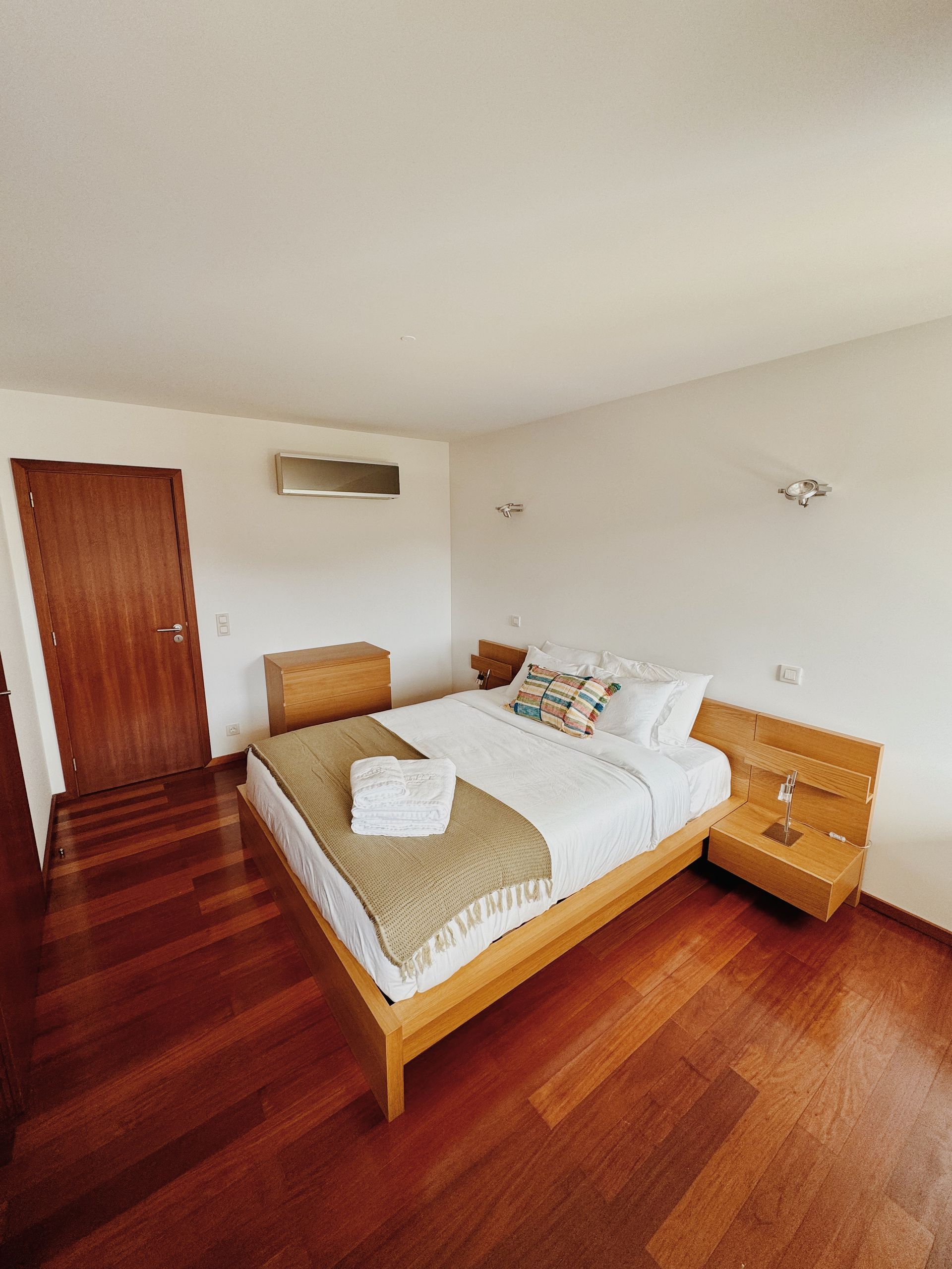 Um quarto com cama grande e piso de madeira