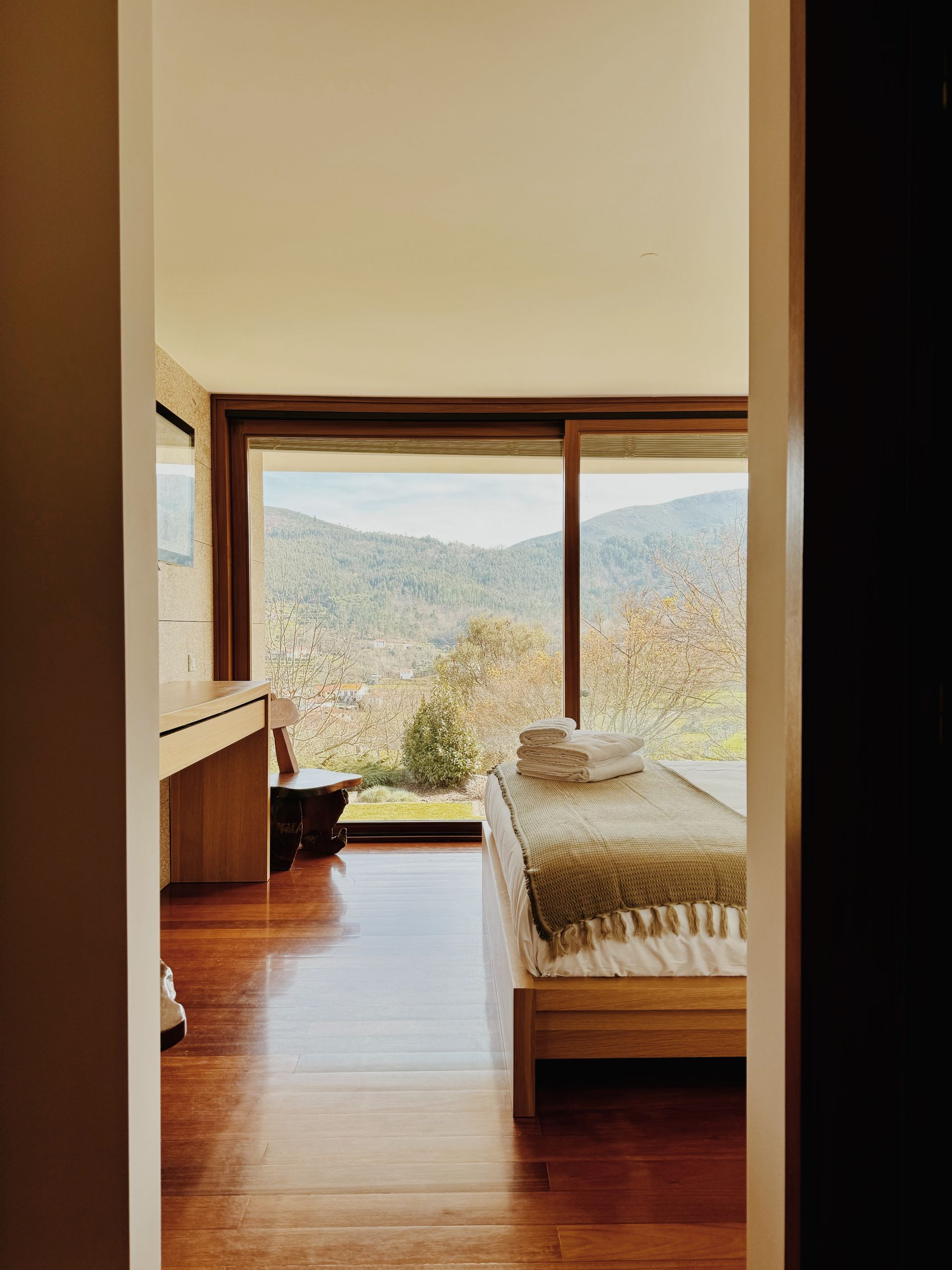 Um quarto com uma cama e uma grande janela com vista para as montanhas.