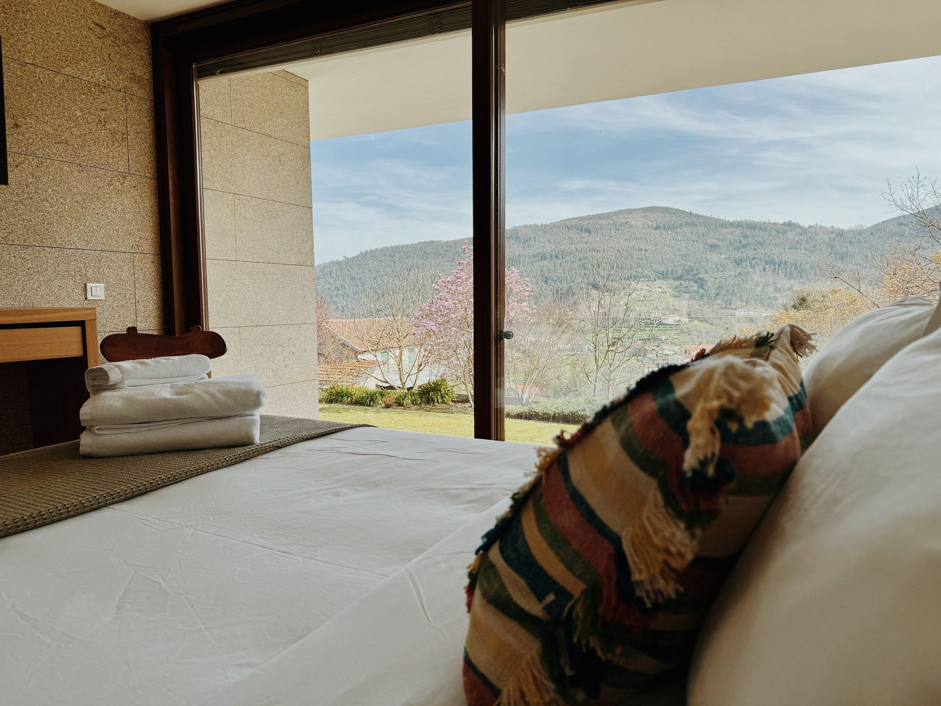 Um quarto com uma grande janela e uma cama com travesseiro.