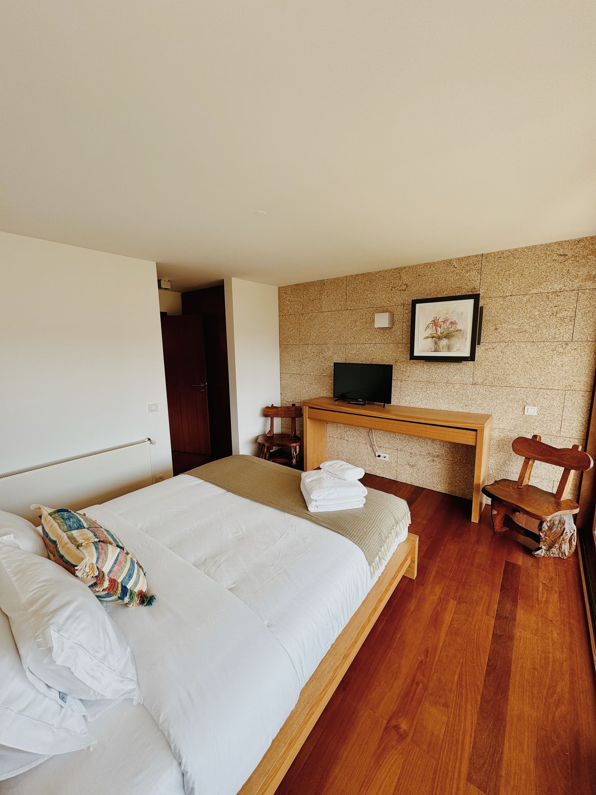 Um quarto com cama, mesa, cadeiras e televisão.