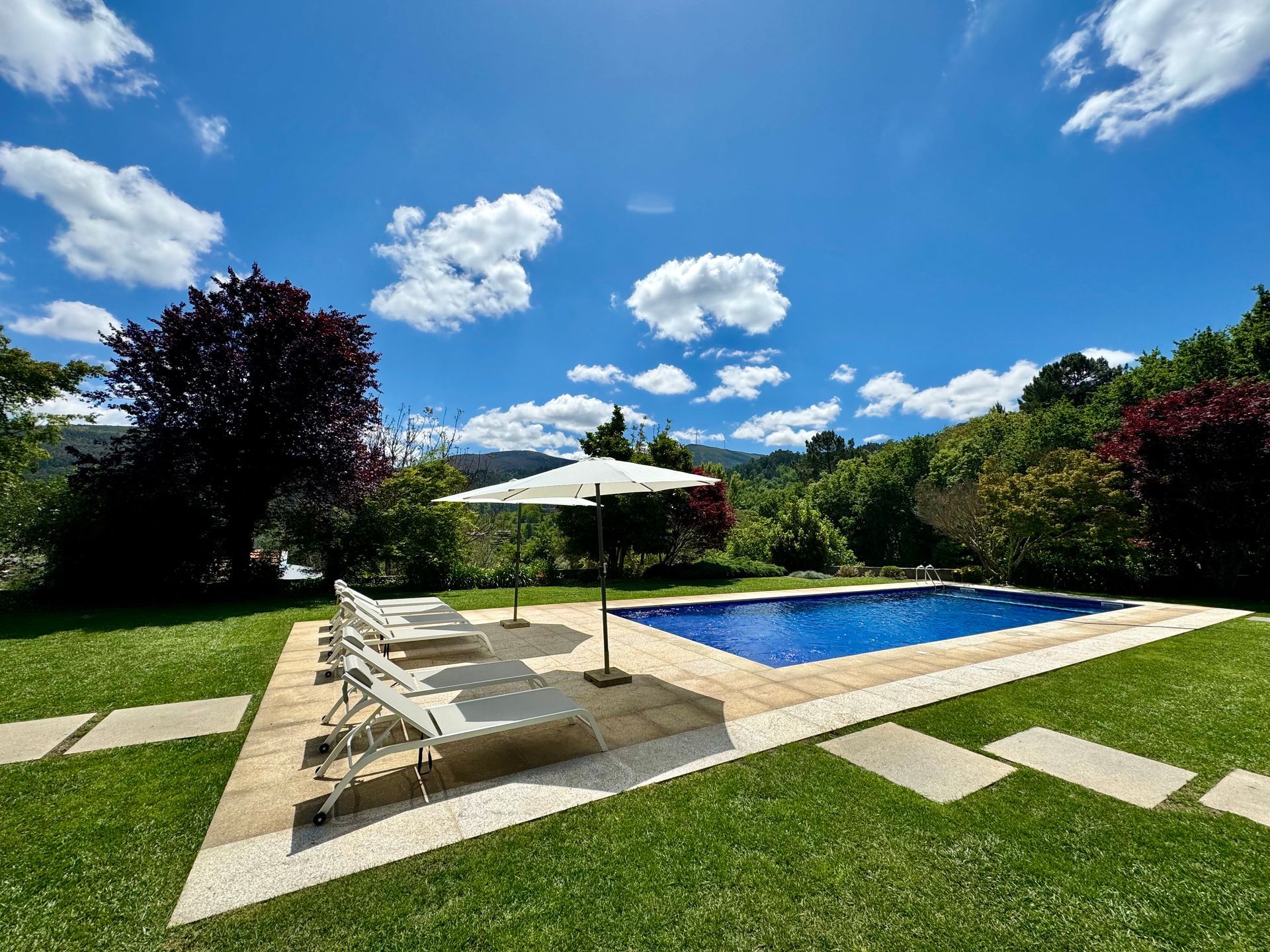 Outdoor swimming pool with long chairs and panoramic mountain view