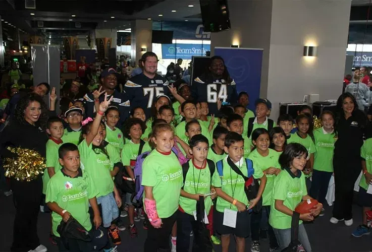 a group of children wearing green team smile shirts.