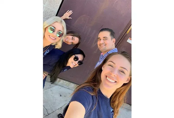 Del Mar Dental staff posing for a picture in front of a brown door.