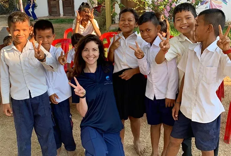 a woman wearing a shirt that says ocean on it poses with a group of children.