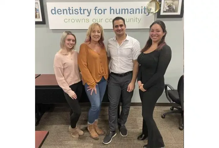 Del Mar Dental Arts staff are posing for a picture in front of a sign that says dentistry for humanity.