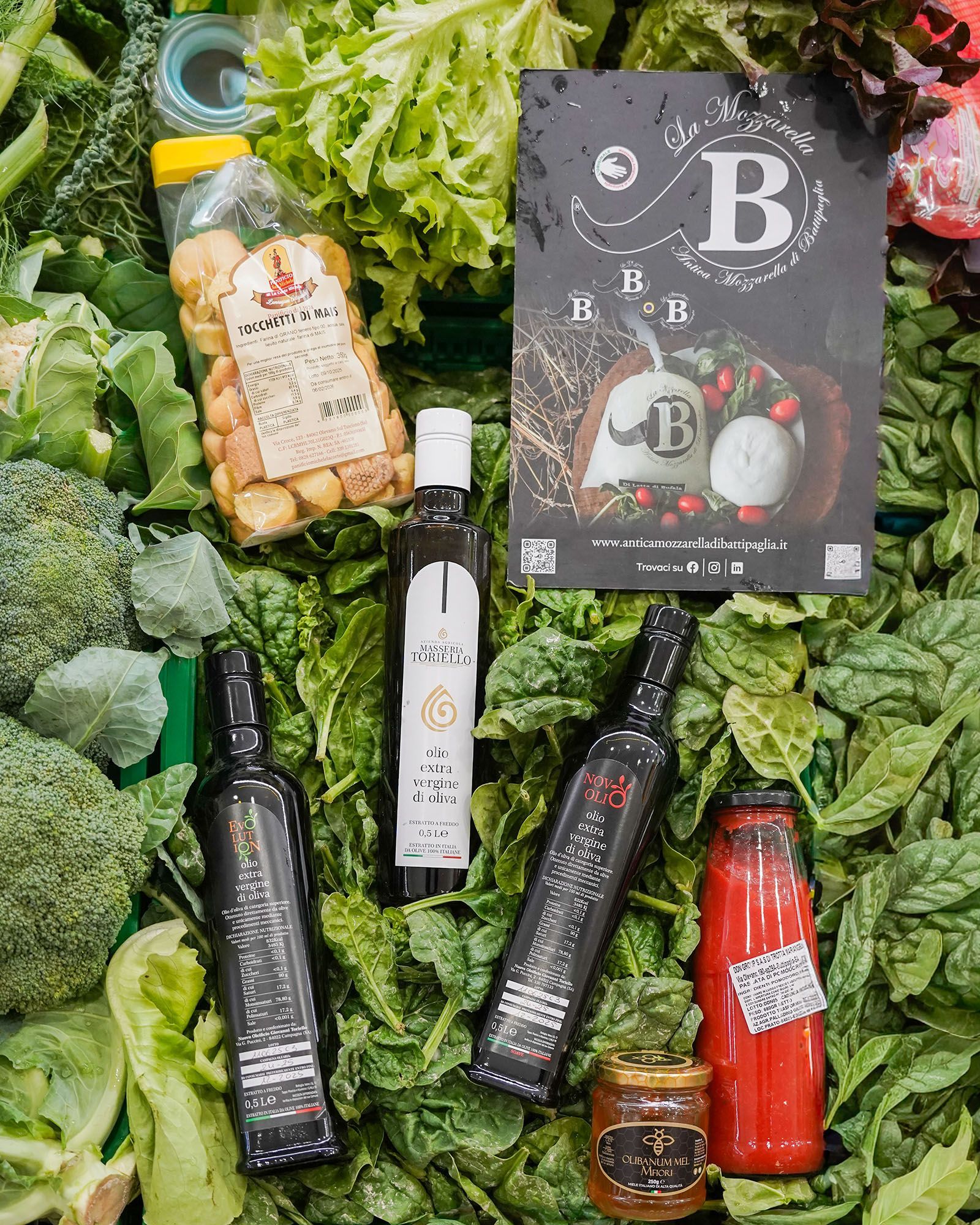 Assortimento di salse in bottiglia e crostini di pane su un letto di verdure fresche con broccoli.