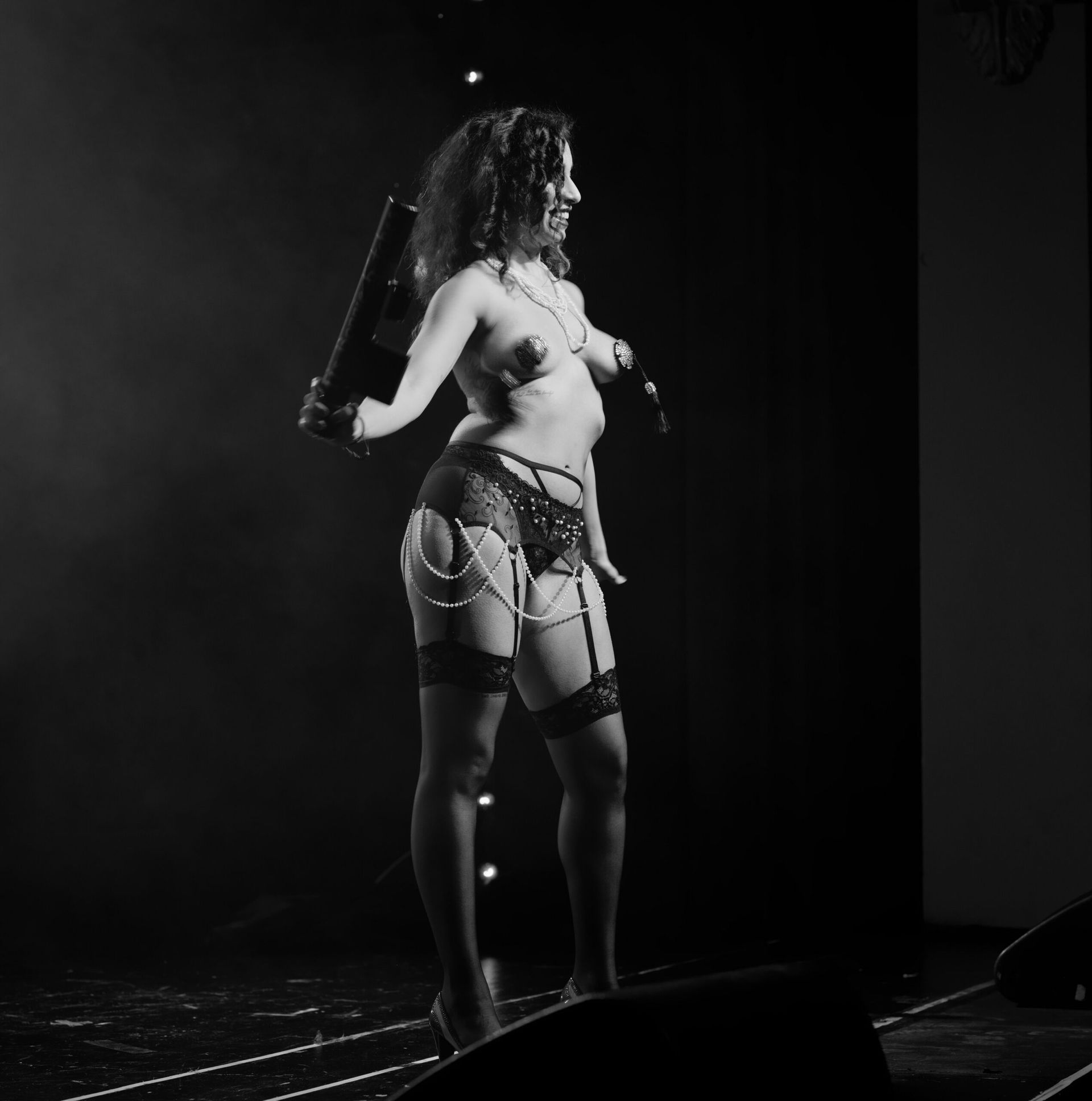 Une femme en lingerie se produit sur scène avec un microphone et un accessoire.