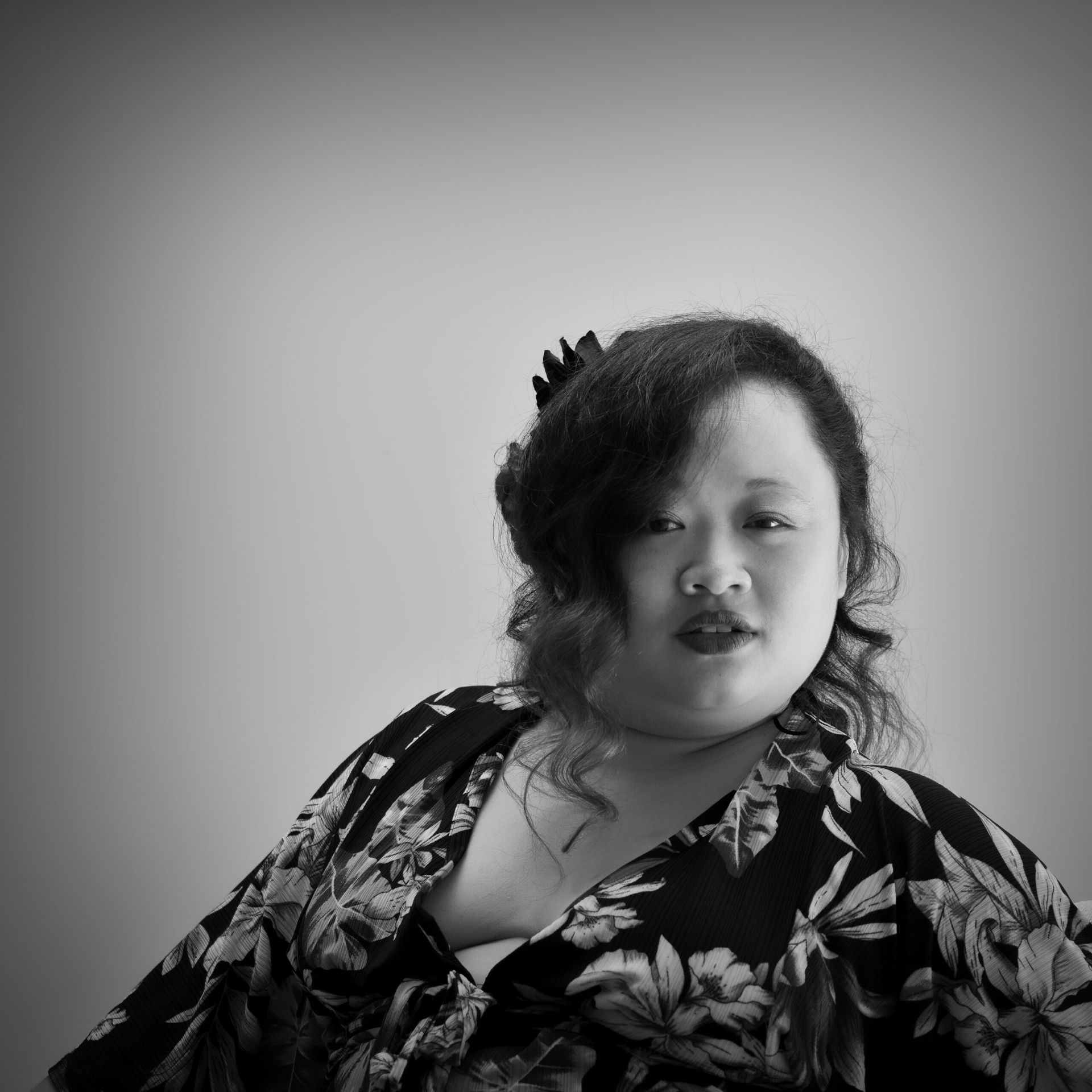 Femme en robe à fleurs, regardant l'objectif. Photo en noir et blanc.