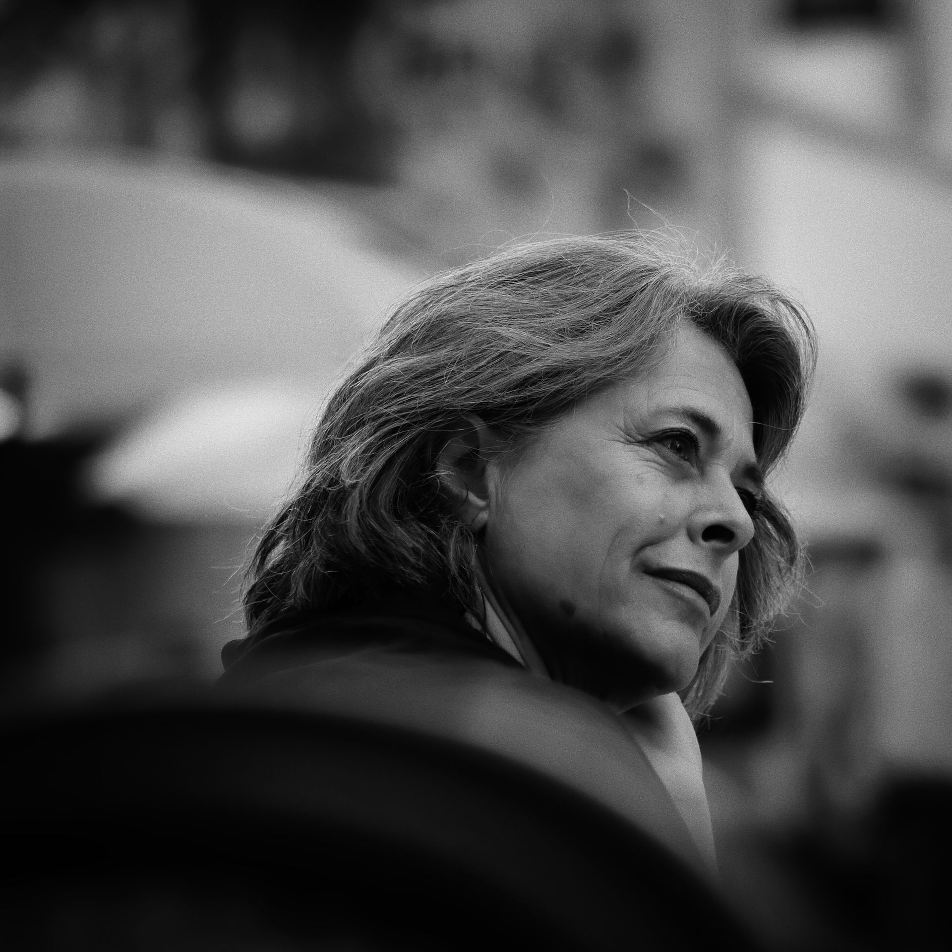 Femme aux cheveux courts, le regard tourné vers l'extérieur, l'air pensif. Noir et blanc, en extérieur.