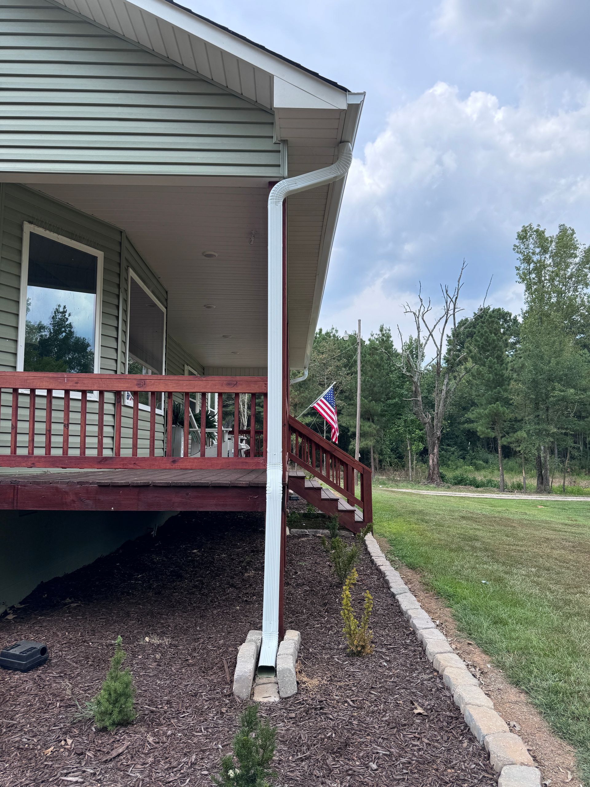 A house with a porch and a rain gutter on the side of it.