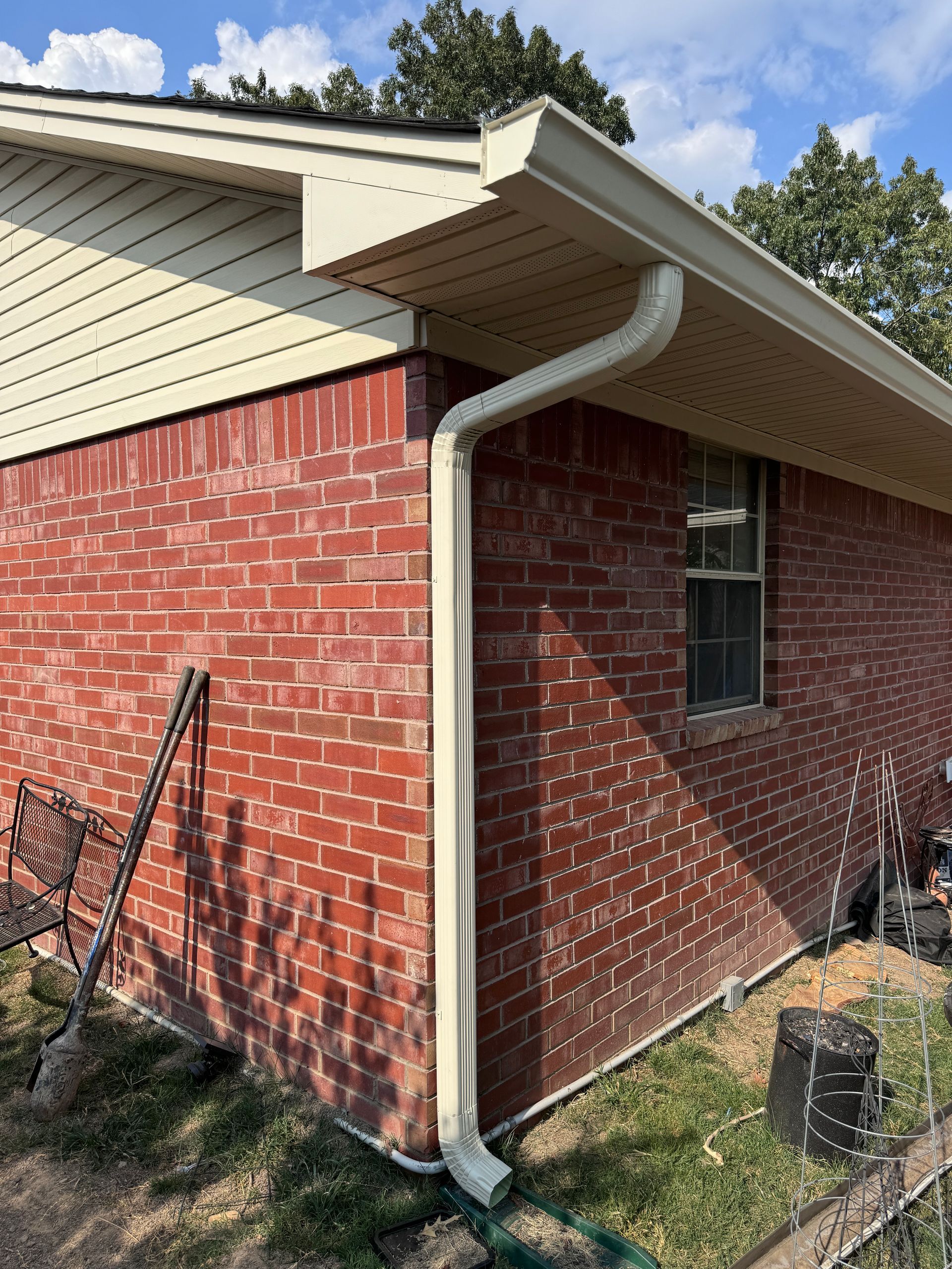 A red brick house with a white gutter on the side of it.