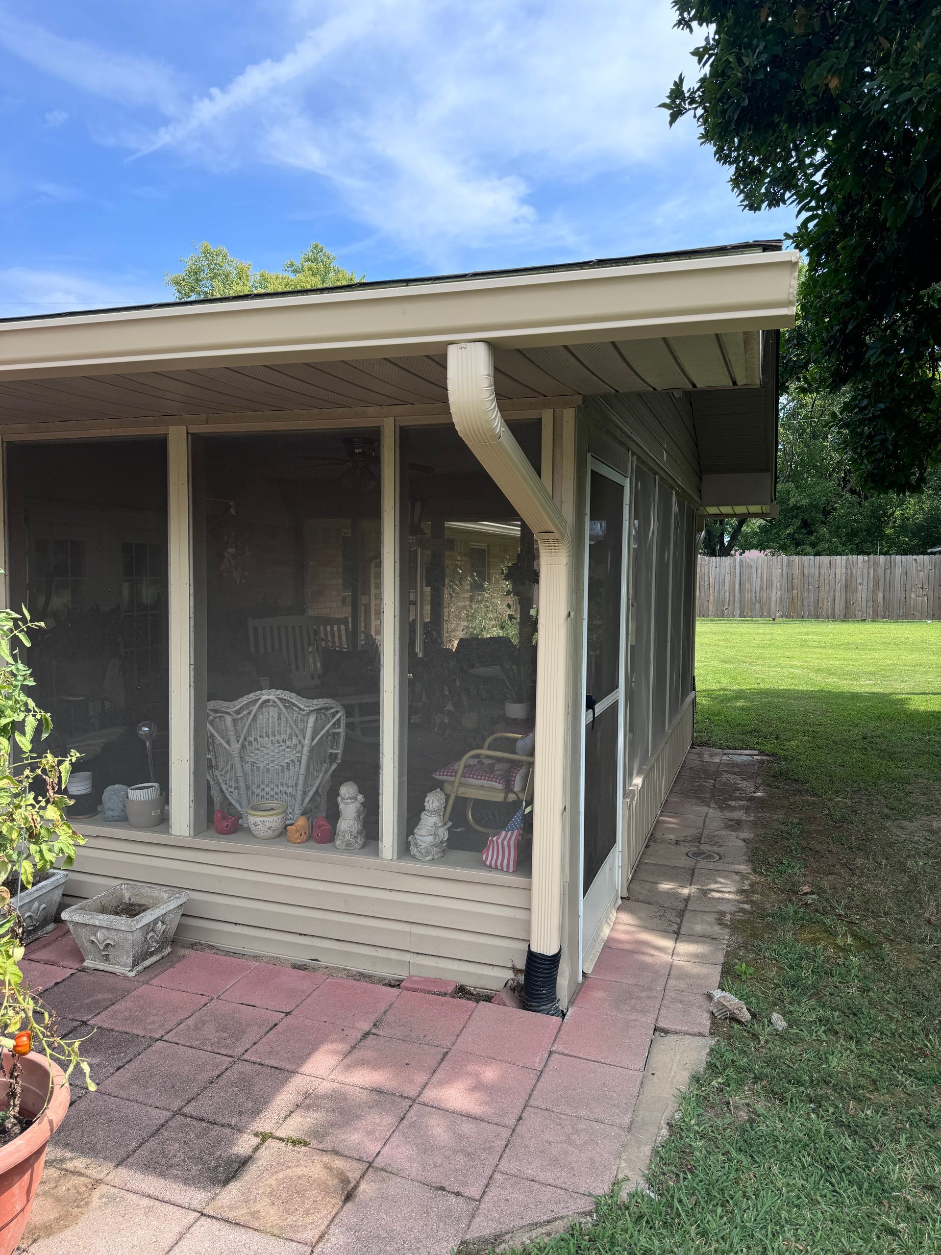 A screened in porch with a chair and a table on it